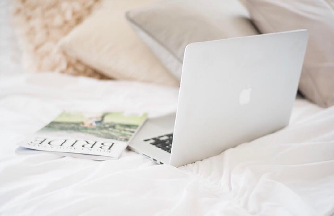 computer on bed with bride magazine