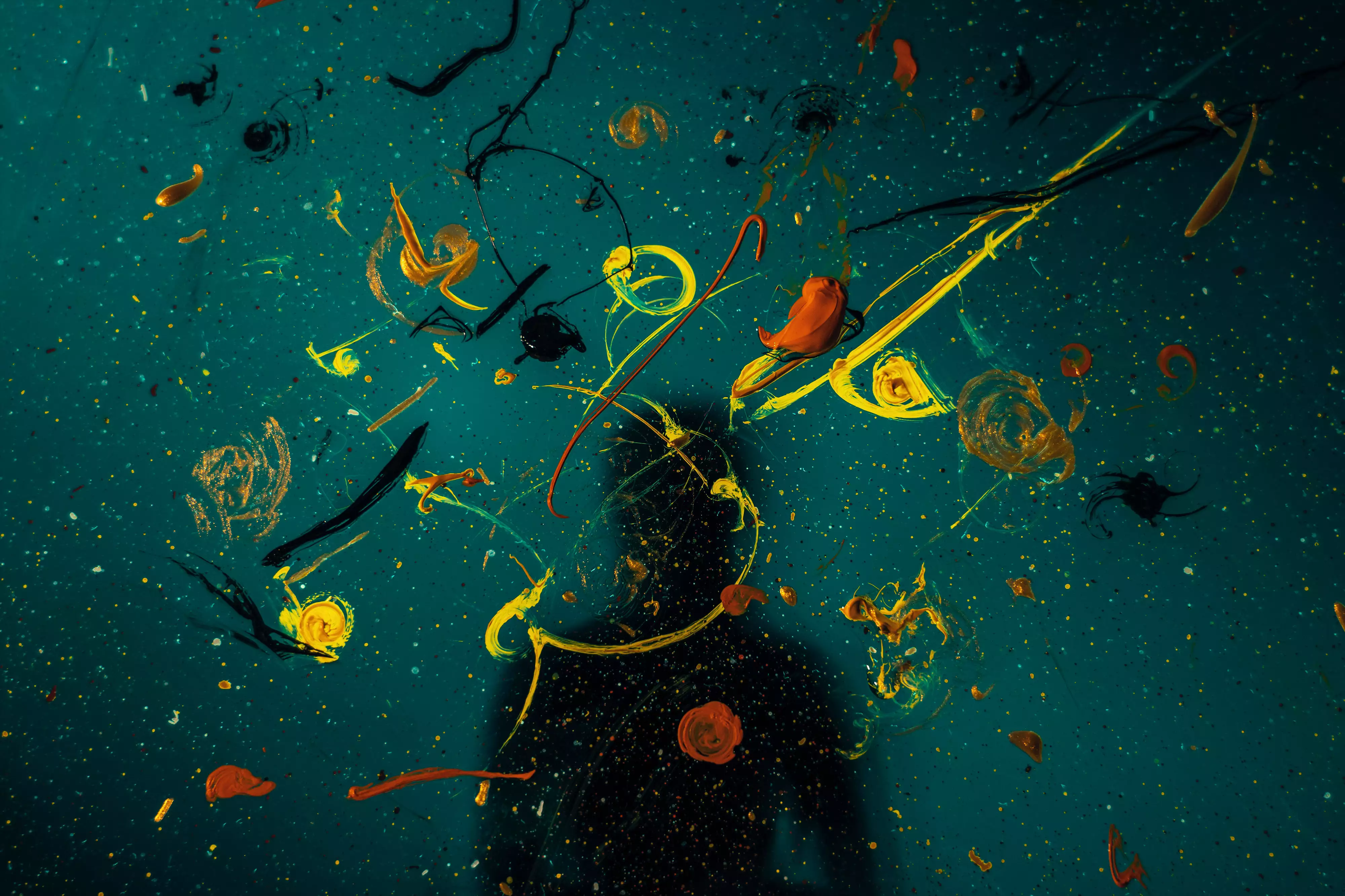 A canvas with paint splattered and a silhouette of a person to illustrate how to cultivate more creativity